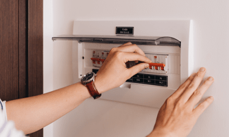 A photograph of a person, who is off camera except for their hands, using their electrical safety switch array.