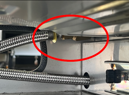 A photograph showing a gas cooktop connecting elbow with a red circle graphic identifying where the connecting elbow is.