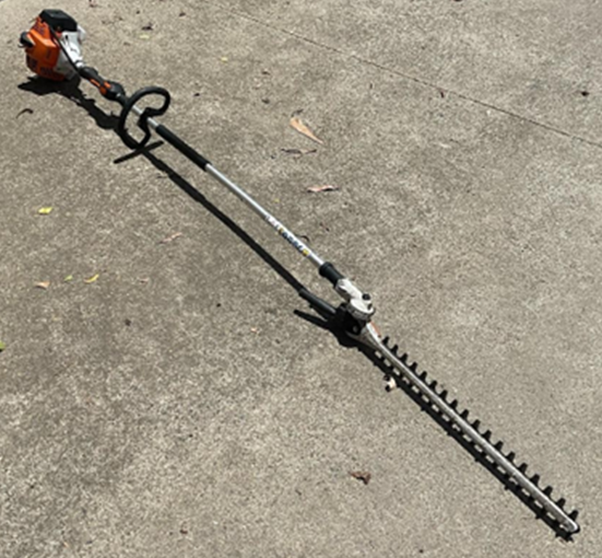 A photograph of a 'hedger' or hedge trimmer. This model is straight, with a saw on one end and the power supply on the other, with a rounded handle.