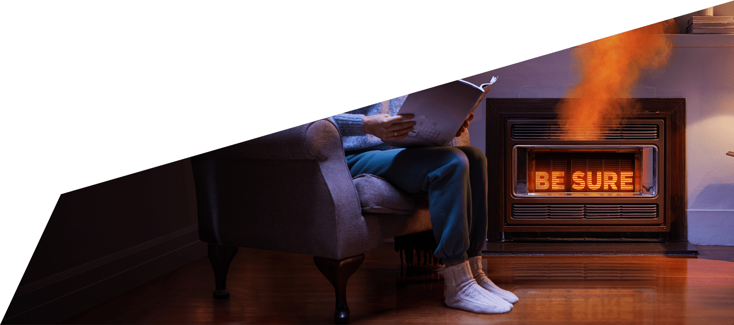 A person reading at a chair next to a faulty gas heater.