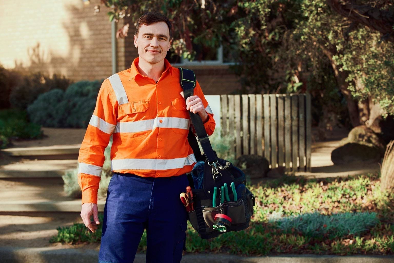 A person in a hi-vis vest standing outside. 
